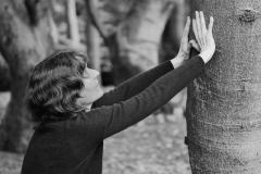 Künstlerin berührt einen Baum - Zuhause in der Natur
