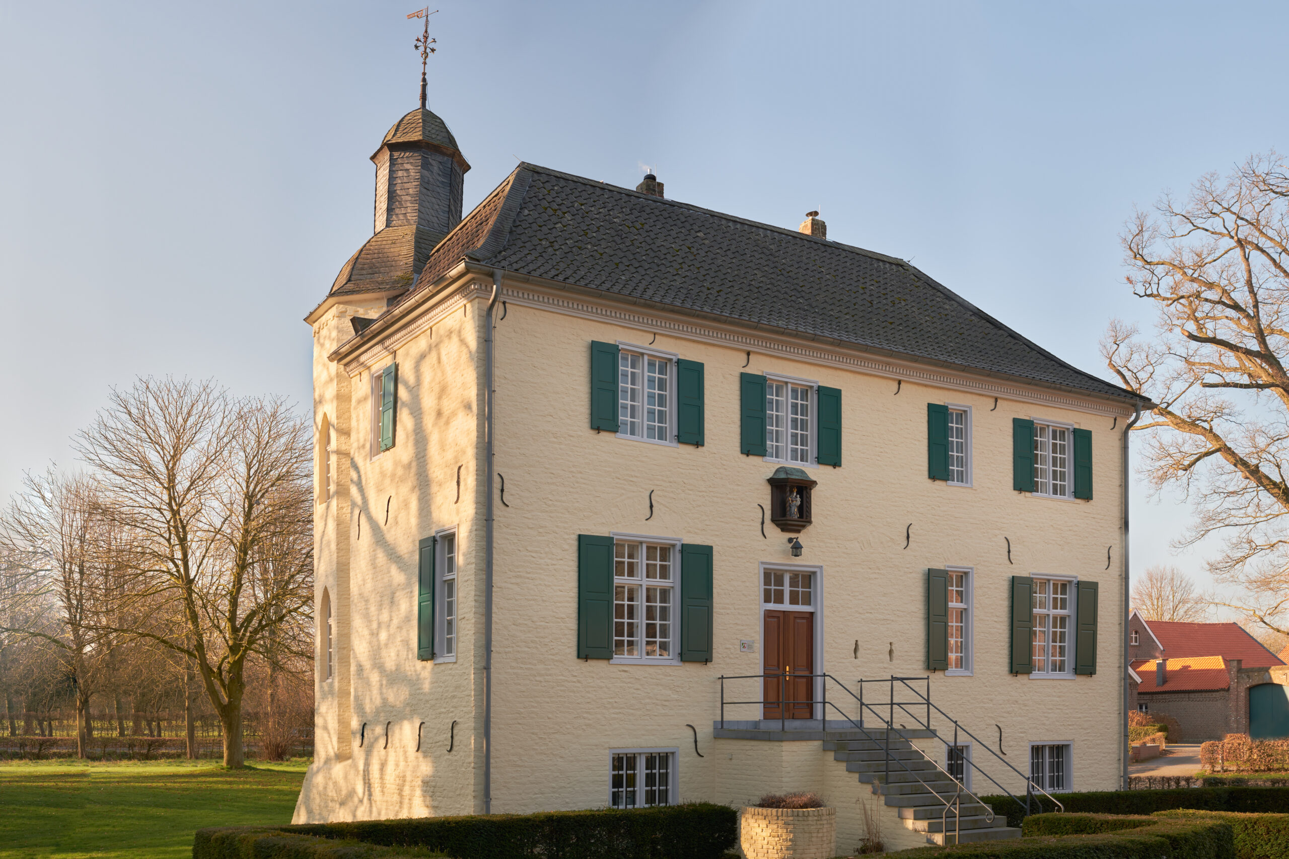 kleines-schloss-gelb-gestrichen-gruene-laeden-im-morgenlicht-vor-wolkenlosem-himmel