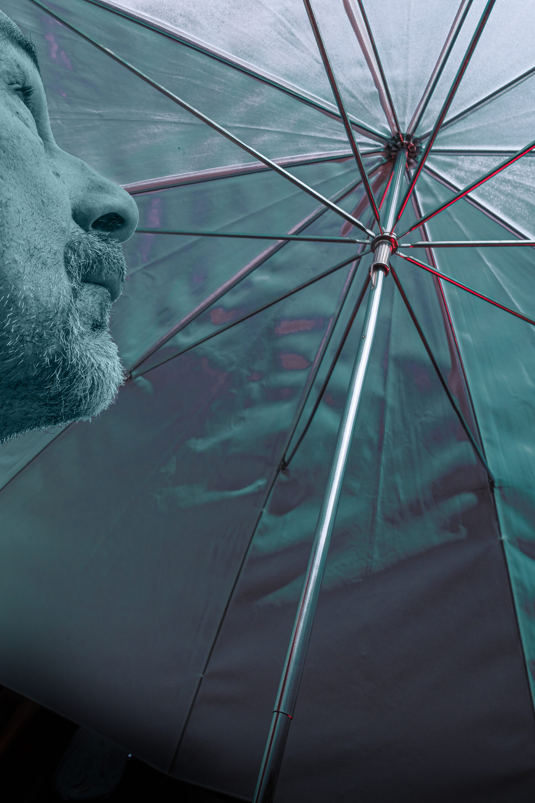 Gesicht eines Mannes blickt von unten auf einen Regenschirm, grün eingefärbt