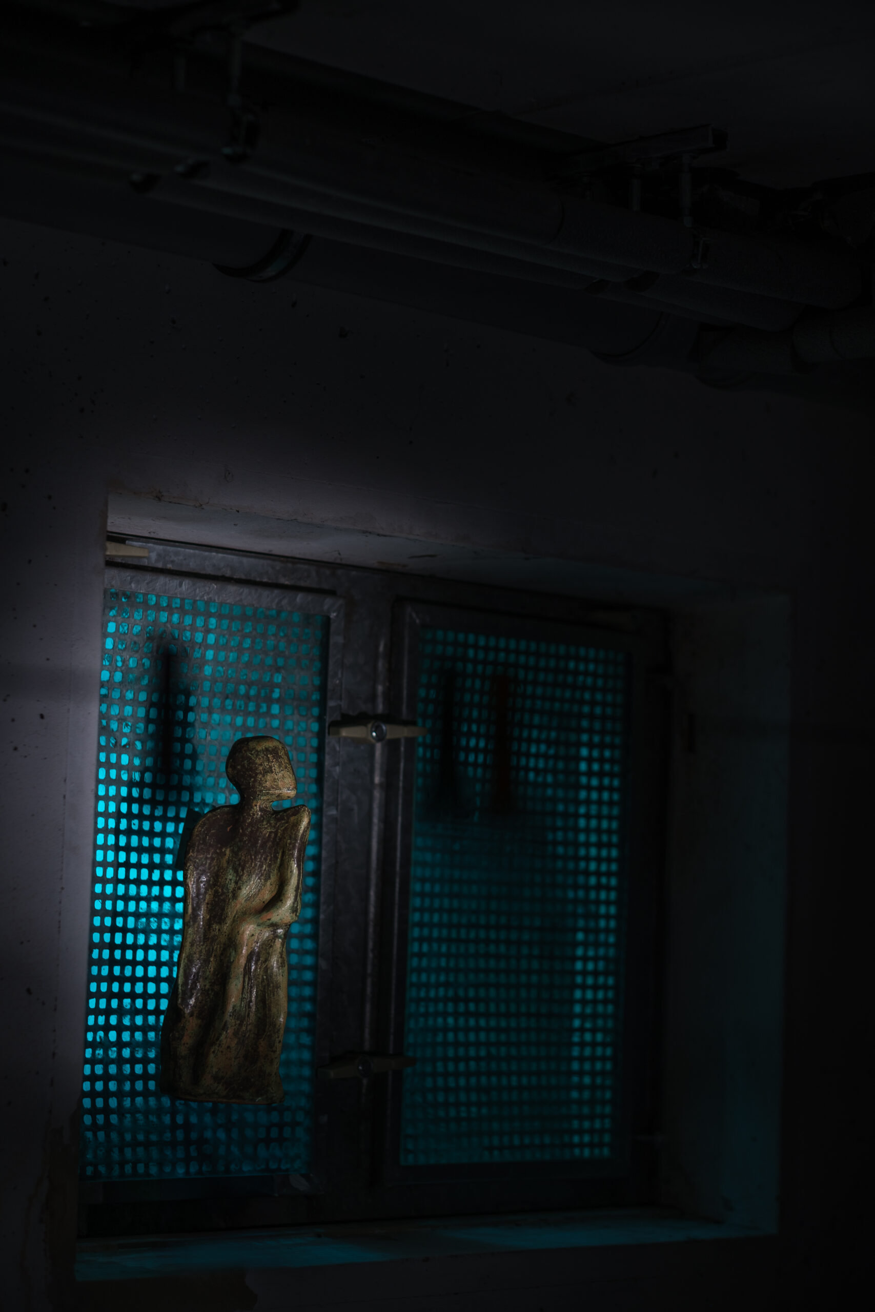 Gefangen Metaphorisches Bild einer Figur aus Ton vor einem illuminierten Kellerfenster