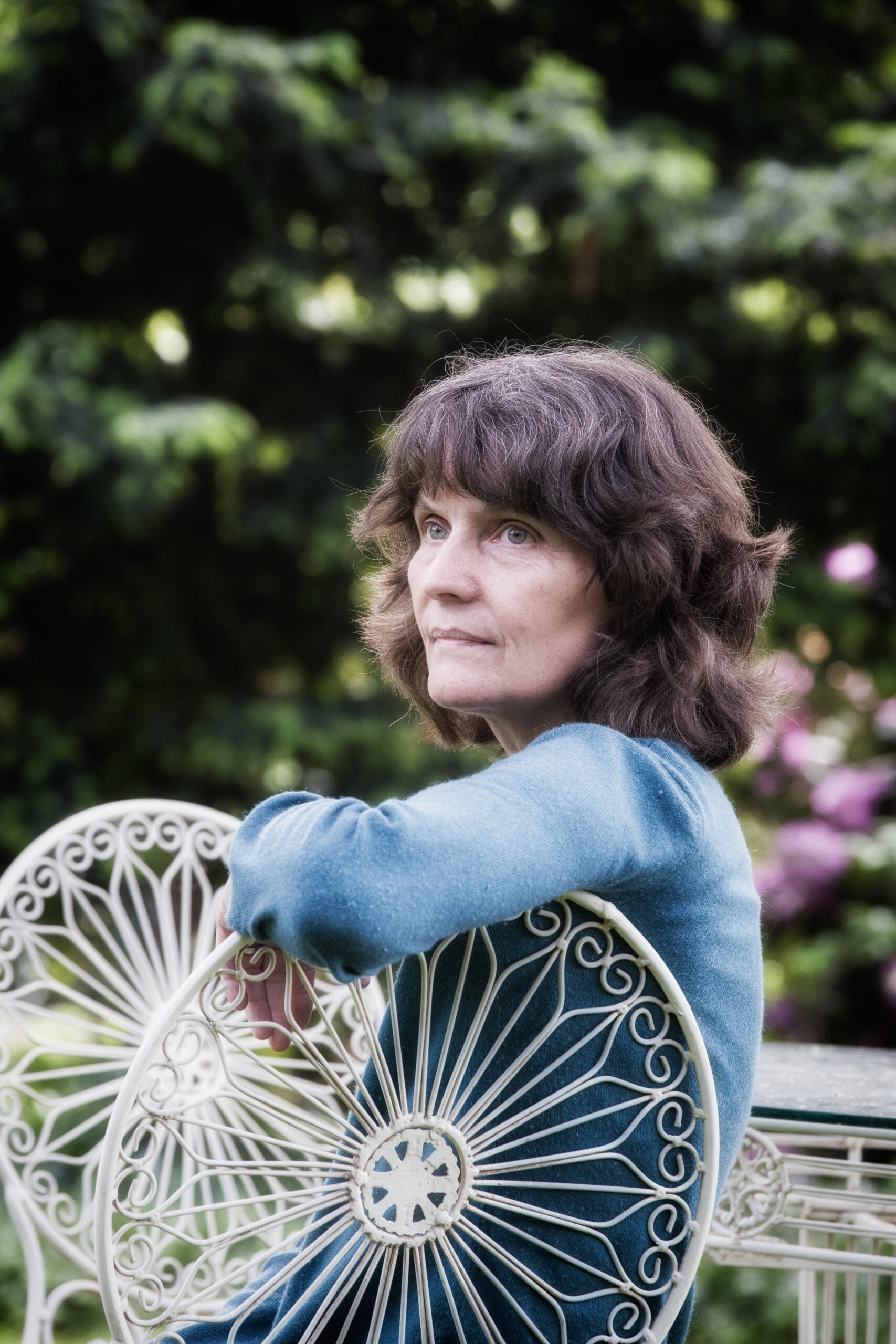 Portrait Porzellankünstlerin Gitta Radtke Nettetaler Porzellankünstlerin Gitta Radke sitzt in ihrem Garten auf weißem Metallstuhl mit filigranen Ornamenten