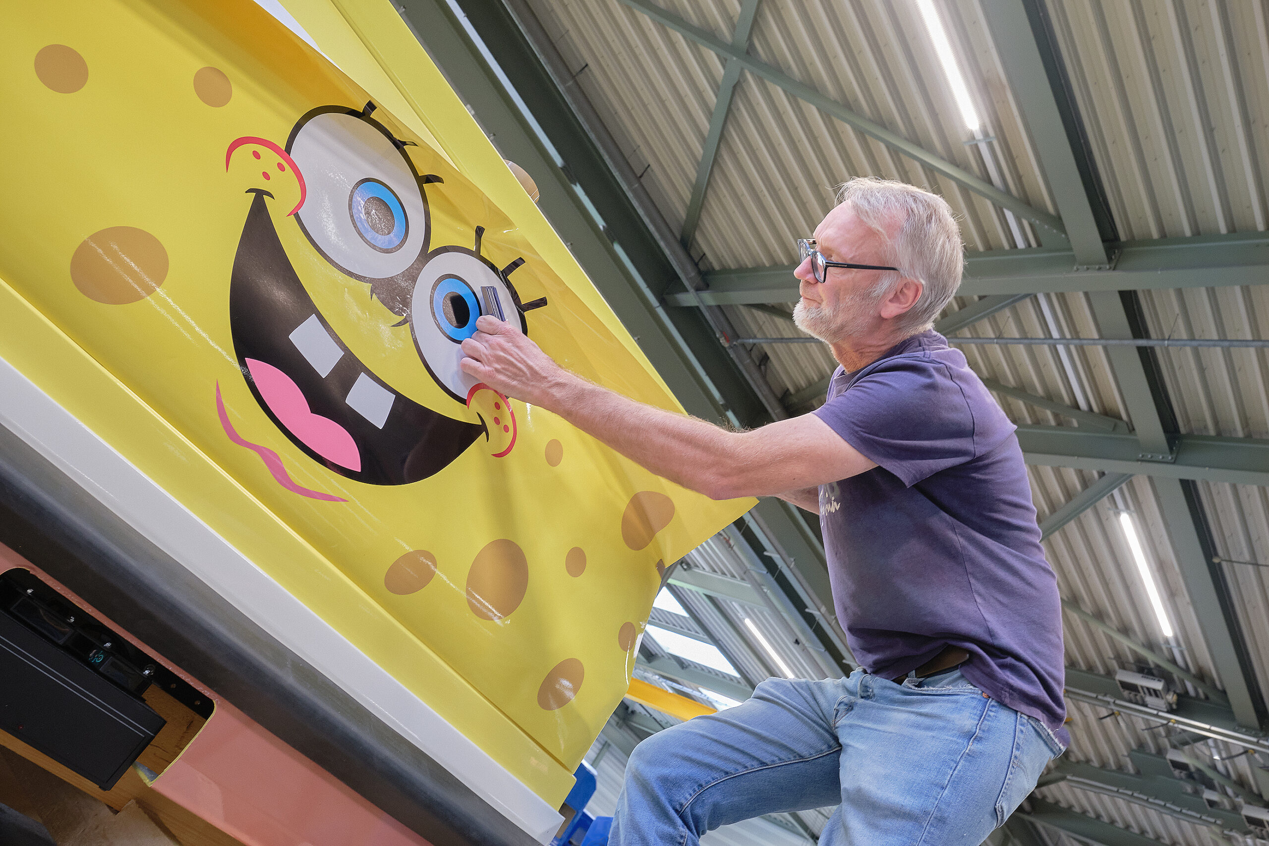 Werbetechniker Mario Verstegen bei der Arbeit Werbetechniker beim Bekleben eines Achterbahnwagens