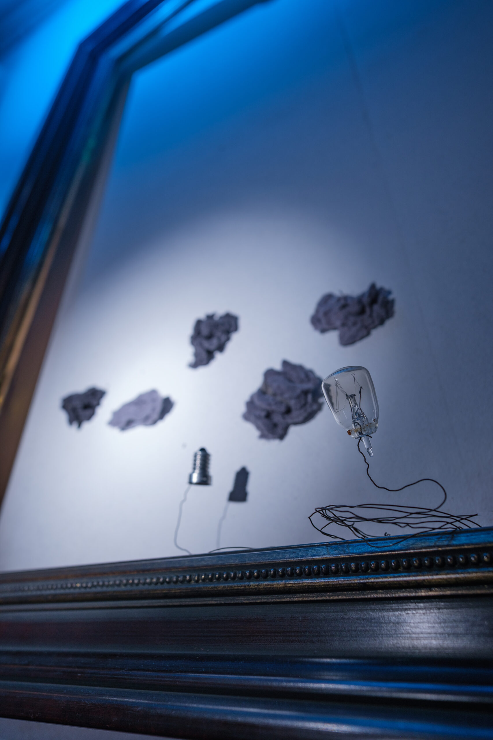 Wolkig ohne Aufheiterung Artwork im Rahmen mit defekter Glühbirne und grauen Wolken als Metapher für negative Gedankenschleifen