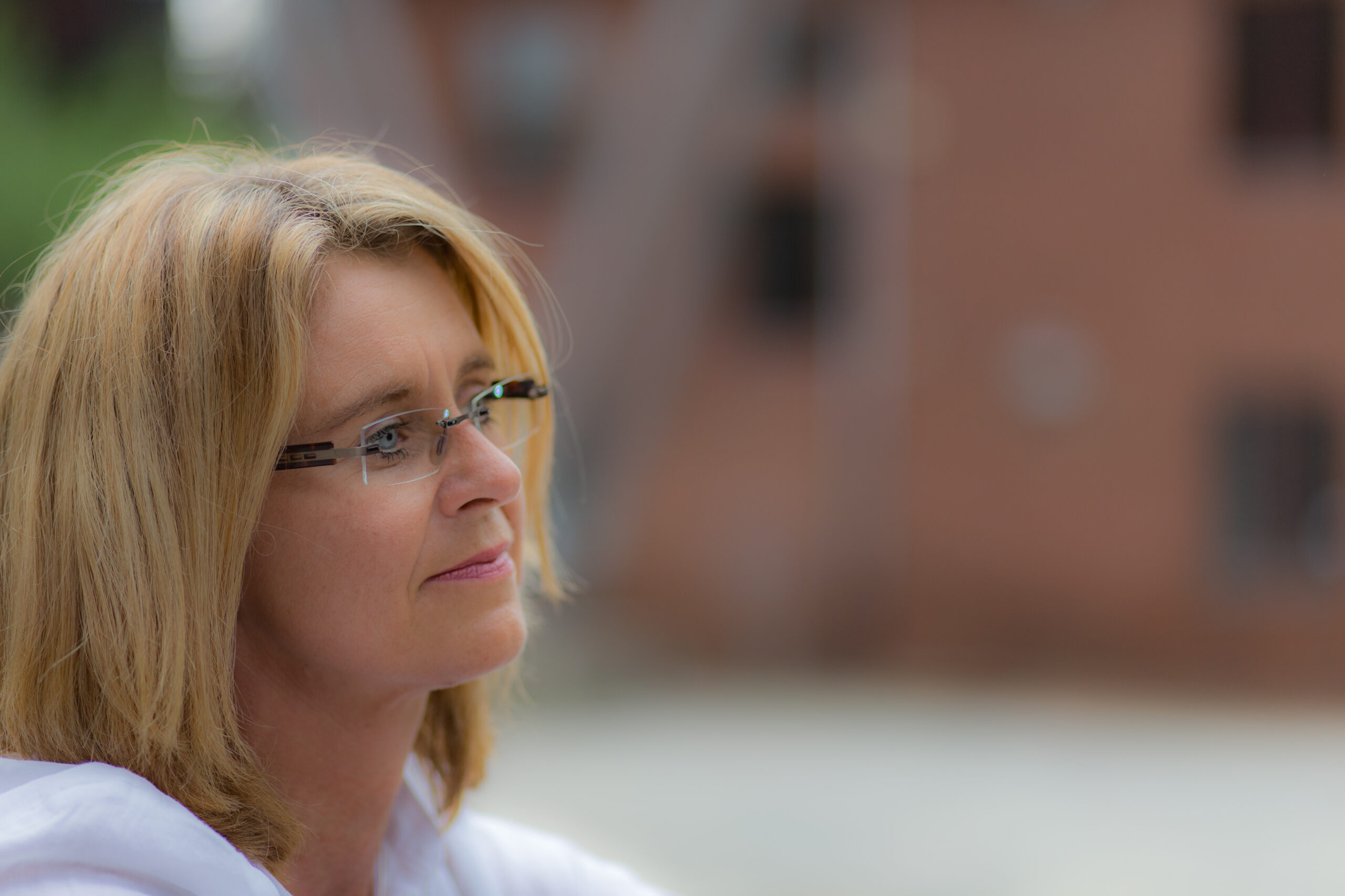 Dreaming of ... Kopfportrait einer Frau mit verträumtem Blick vor unscharfem Hintergrund